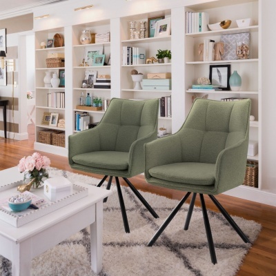 Duas cadeiras verdes com pernas pretas em sala com estantes brancas e decoração