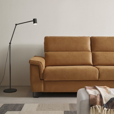 Sofá de couro castanho com luminária de pé preta e parede clara no fundo