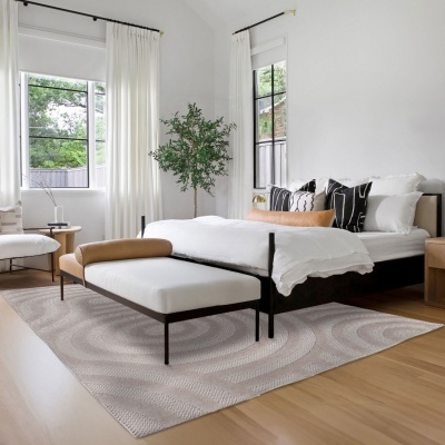 Quarto moderno com cama de ferro preta, almofadas decorativas e banco estofado branco com apoio castanho