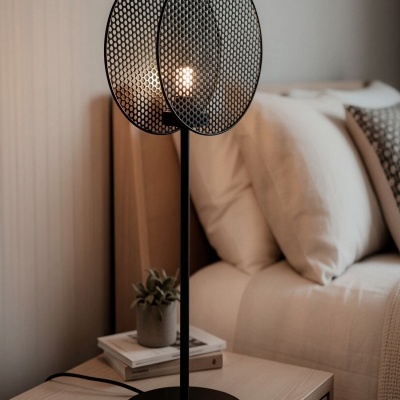 Candeeiro de mesa preto com difusores de malha sobre mesa de cabeceira de madeira clara