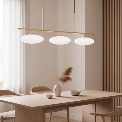 Luminária pendente dourada com globos brancos sobre mesa de madeira clara e cadeiras, vaso e bowl no centro, ambiente neutro