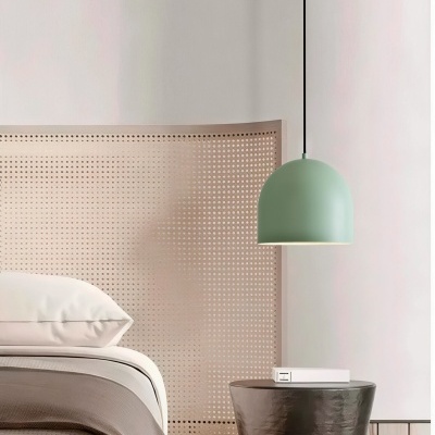 Cabeceira de cama em madeira clara com furos redondos, cama com almofada branca e edredão bege, mesas castanho escuro com candeeiro pendente verde e caixa branca.