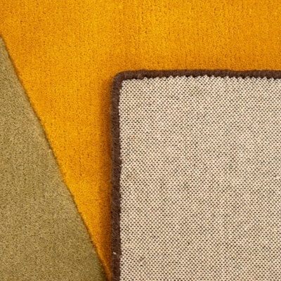 Tapete verso bege com borda castanha sobre tapetes mostarda e verde