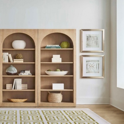 Estante dupla de madeira clara com decoração minimalista e duas molduras abstratas prateadas na parede