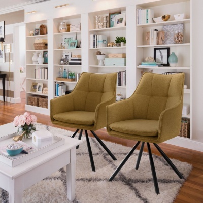 Sala de estar com duas cadeiras cor mostarda, mesa de centro branca, tapete branco e estantes brancas com decoração