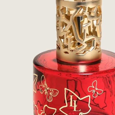 Frasco vermelho decorado com tampa dourada recortada e desenhos dourados de folhas e borboletas