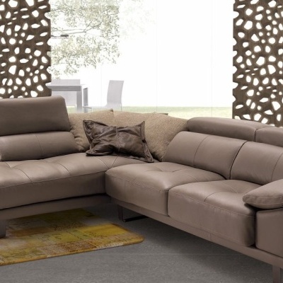 Sofá de canto castanho em pele com almofadas e decorativos em sala moderna