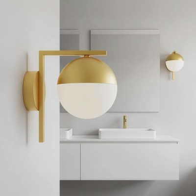 Lâmpada de parede dourada e branca junto a lavatório branco com torneira dourada e espelho.