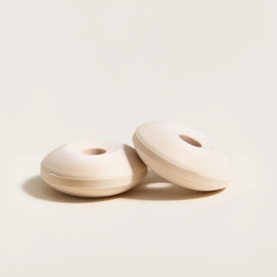 Dois objetos redondos creme com forma de donuts sobre superfície clara