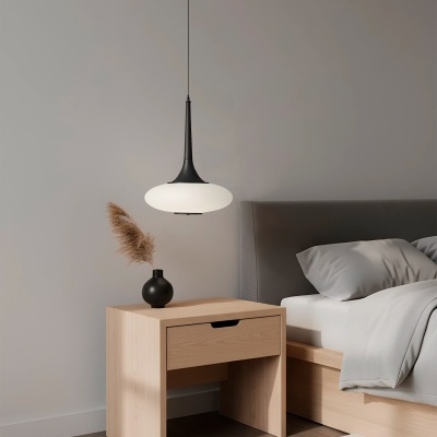 Mesa de cabeceira de madeira clara com vaso preto e luminária suspensa branca e preta ao lado de cama cinza
