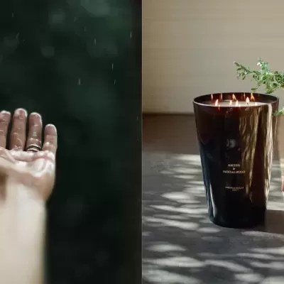 Mão sob chuva e vela preta com texto DS junto a cadeira e planta