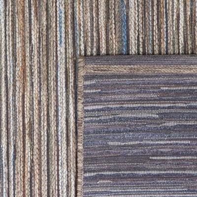 Tapetes sobrepostos com padrões de riscas em tons castanhos, cinzentos e azuis