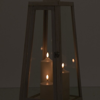 Lanterna de madeira clara com vidro e três velas acesas no interior.