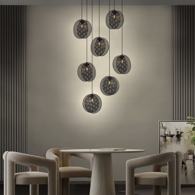 Lustre de teto preto com cúpulas de tela metálica suspenso sobre mesa redonda de madeira clara com cadeiras bege ao redor