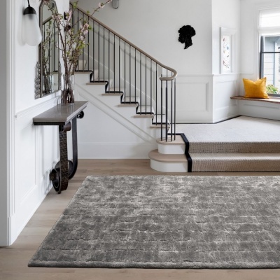 Tapete cinzento geométrico em sala com escadas de madeira e metal, mesa de consola e almofada amarela