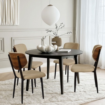 Mesa redonda preta com quatro cadeiras bege e madeira numa sala clara e moderna