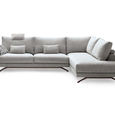 Sofá canto em tecido cinza com almofadas e patas metálicas.