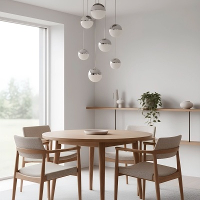 Mesa de madeira redonda com quatro cadeiras estofadas em tecido bege e candeeiros pendentes metálicos prateados e brancos num ambiente minimalista