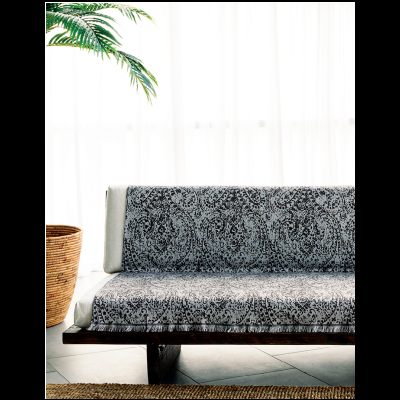 sofá branco com manta cinza e preta, planta em vaso de palha, cortinas brancas