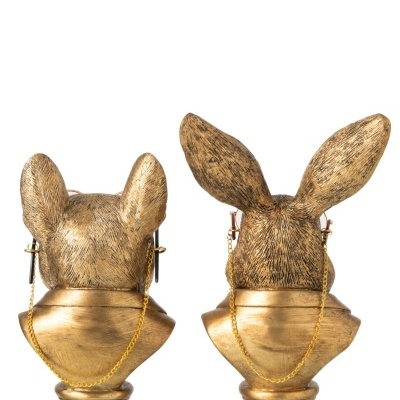 Esculturas douradas de cabeças de animais com orelhas distintas e correntes douradas penduradas.