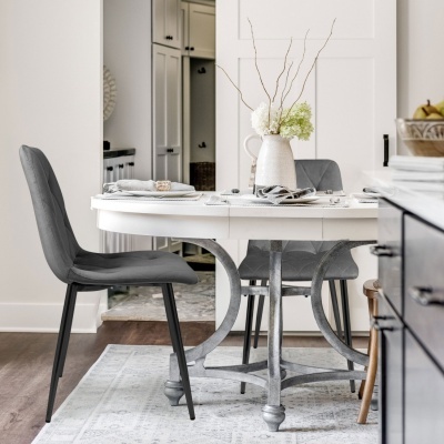 Mesa de jantar branca com cadeiras cinzentas e jarra com flores