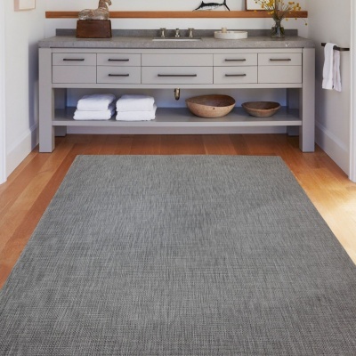 Tapete cinzento diante de móvel de casa de banho cinzento com toalhas e tigelas de madeira