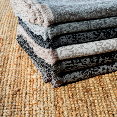 Mantinhas dobradas com padrão floral e franjas sobre tapete de textura grossa