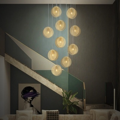 Lustre pendente dourado com globos perfurados em sala moderna com sofá e escada