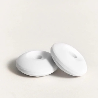 Dois objetos brancos redondos com furo central sobre superfície branca