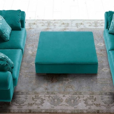 Sala de estar com sofás e puff verde esmeralda em veludo com almofadas decorativas e tapete cinza