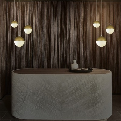Lustres pendentes dourados com globos de luz LED suspensos em espaço com mesa oval cinzenta e parede castanha texturada