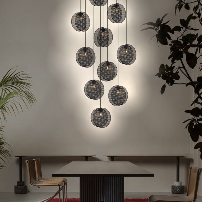 Lustres suspensos redondos pretos com luz, mesa preta, cadeiras bege com estrutura metálica, tapete vermelho e plantas