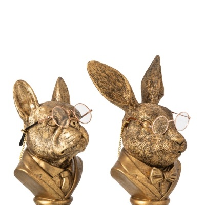 Estatuetas douradas de bronze de um cão e um coelho com óculos.