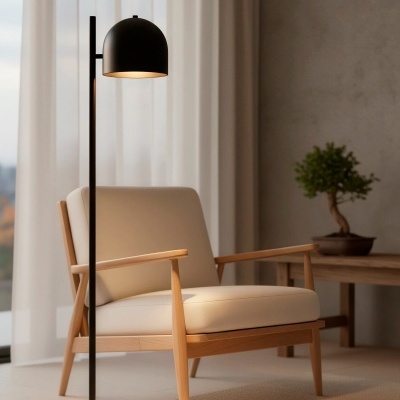 Poltrona de madeira clara e estofado creme com luminária preta ao lado em ambiente interior