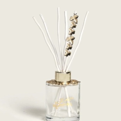 Difusor de fragrância em vidro transparente com hastes brancas e decoração dourada