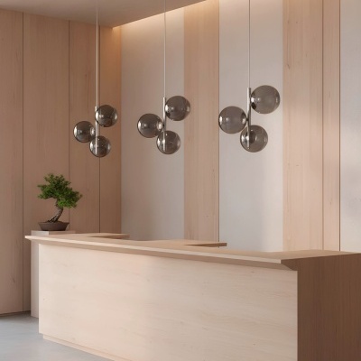 Balcão de madeira clara com candeeiros suspensos de vidro fumado e planta numa sala moderna