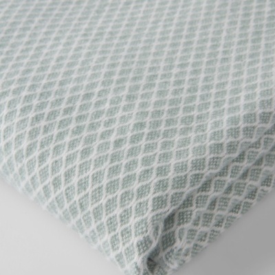 Cobertor azul claro com padrão em rede sobre superfície branca