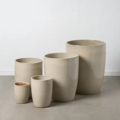 Cinco vasos cerâmicos bege de vários tamanhos com acabamento brilhante