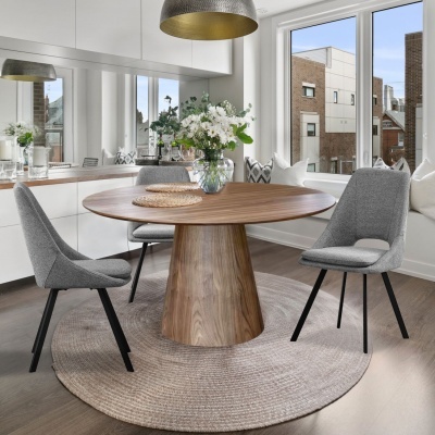 Sala de jantar com mesa redonda de madeira, cadeiras cinza, vaso com flores e janela