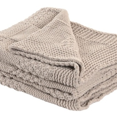 Cobertor ou manta bege com textura de malha grossa e padrão variado