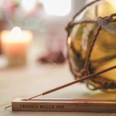 Incensário de madeira com incenso e vela acesa em ambiente decorativo