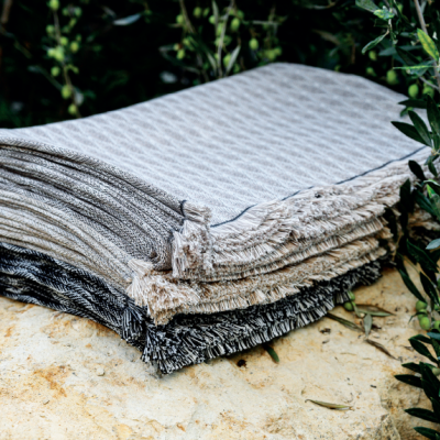 Mantas ou cobertores cinzentos dobrados sobre pedra com plantas verdes ao fundo