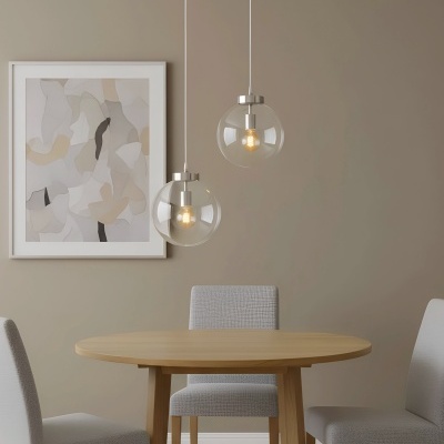 Conjunto de mesa de jantar redonda em madeira clara com cadeiras cinza claro, lâmpadas pendentes de vidro e quadro abstrato neutro na parede bege