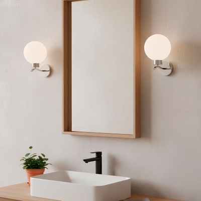 Lavatório branco retangular sobre móvel de madeira com espelho e arandelas redondas com luz e planta em vaso