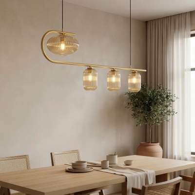 Lustre suspenso dourado com quatro candeeiros de vidro corrugado numa sala de jantar minimalista com mesa e cadeiras de madeira clara e planta em vaso terracota.