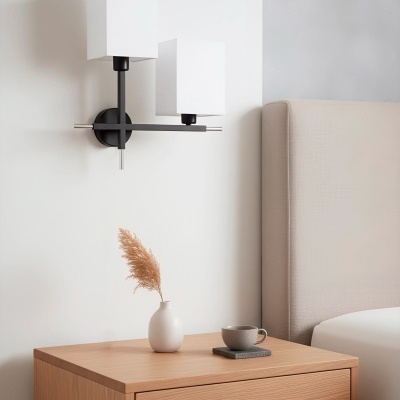 Abajur de parede moderno branco e negro junto a mesa de cabeceira de madeira clara com vaso branco e chávena cinzenta