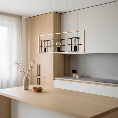 Luminária pendente dourada com cubos pretos e lâmpadas, bancada e armários de cozinha em madeira clara e branco, vaso com flores cor-de-rosa.