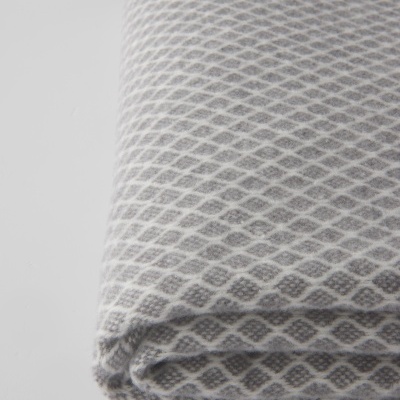 Manta dobrada padrão losangos cinza e branco