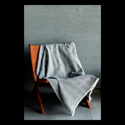 Manta cinza com padrão quadriculado sobre cadeira de madeira e couro marrom