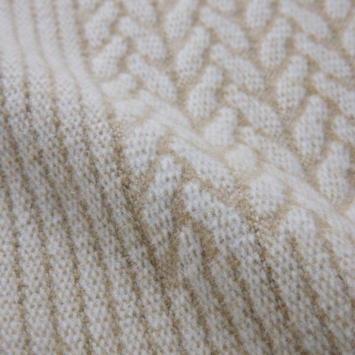 Pano têxtil bege e branco com padrão trançado detalhado